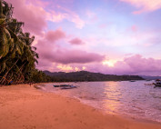 Boats at anchor under a pink sunset on Port Barton beach, the evening before the boat expedition to El Nido