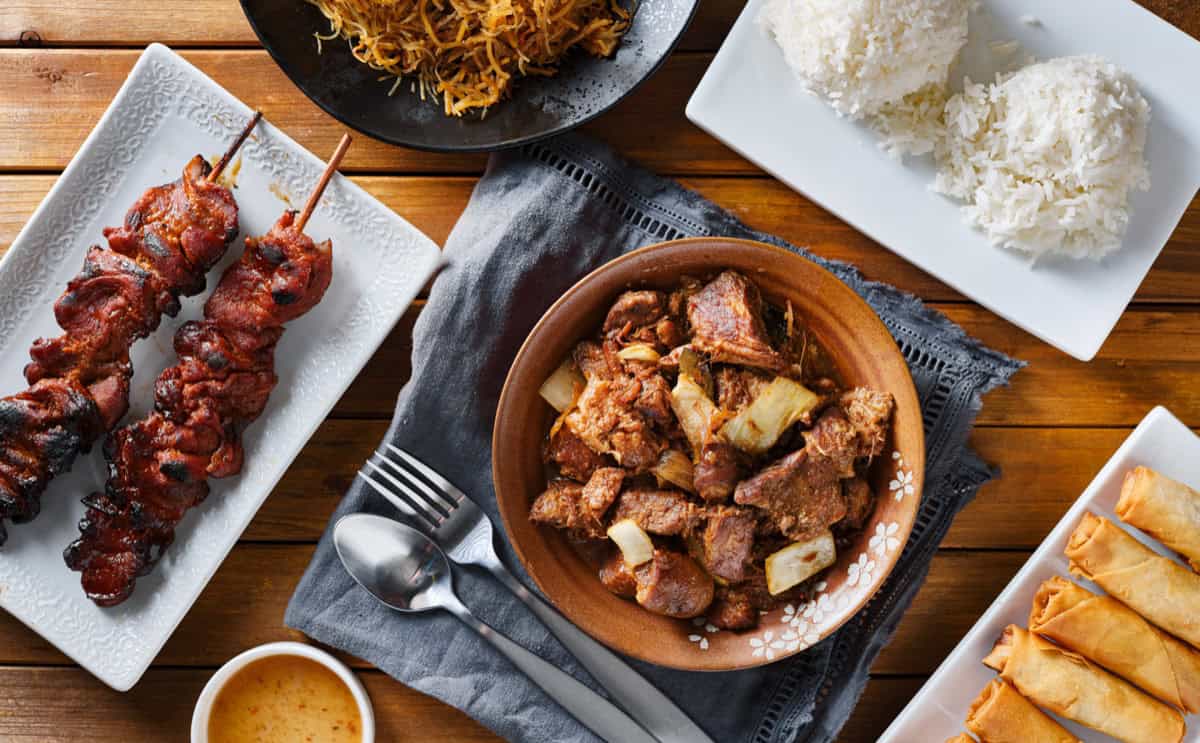 Filipino food spread — pork BBQ, adobo, lumpia and rice Filipino feast — pork BBQ skewers, adobo, lumpia and rice