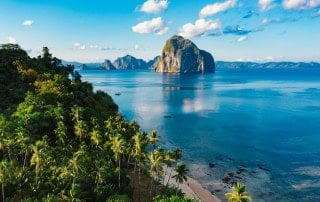 El Nido bay with karst island and palm-fringed coast at golden hour
